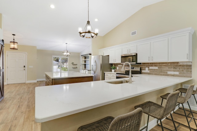 kitchen featuring white cabinetry, stainless steel appliances, tasteful backsplash, pendant lighting, and a center island