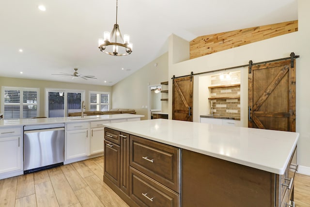 kitchen with a barn door, stainless steel dishwasher, sink, white cabinetry, and ceiling fan with notable chandelier