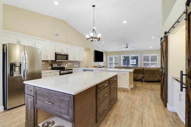 kitchen featuring a barn door, pendant lighting, kitchen peninsula, white cabinetry, and appliances with stainless steel finishes