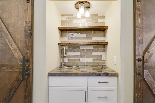 kitchen with white cabinetry, backsplash, and sink