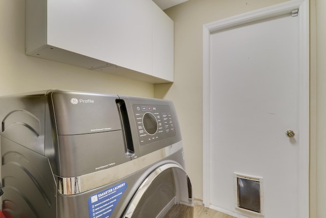 clothes washing area with light wood-type flooring, cabinets, and washing machine and dryer