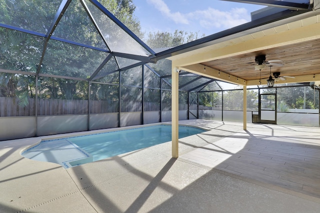 view of swimming pool with glass enclosure, ceiling fan, and a patio