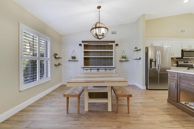 dining space featuring an inviting chandelier, lofted ceiling, and light wood-type flooring