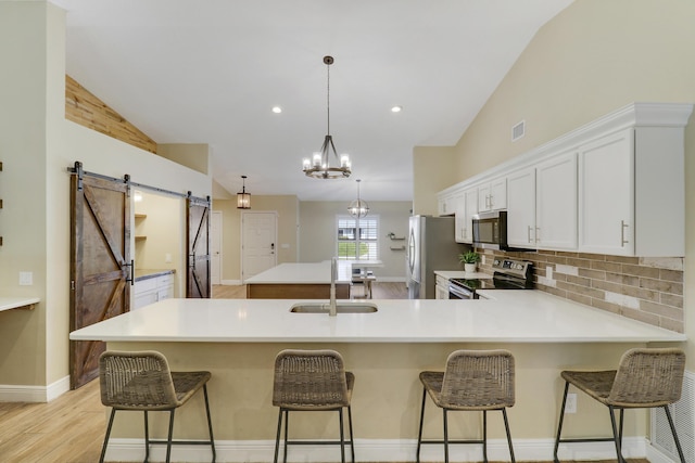 kitchen featuring stainless steel appliances, lofted ceiling, a barn door, and sink