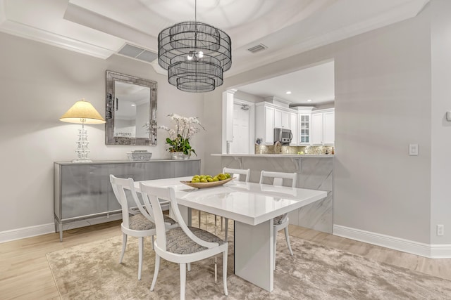 dining space featuring crown molding, light hardwood / wood-style flooring, and a chandelier