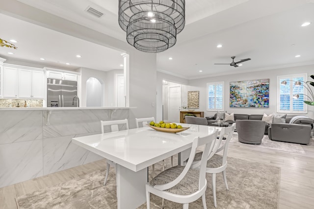 dining room with crown molding, ceiling fan, and light wood-type flooring