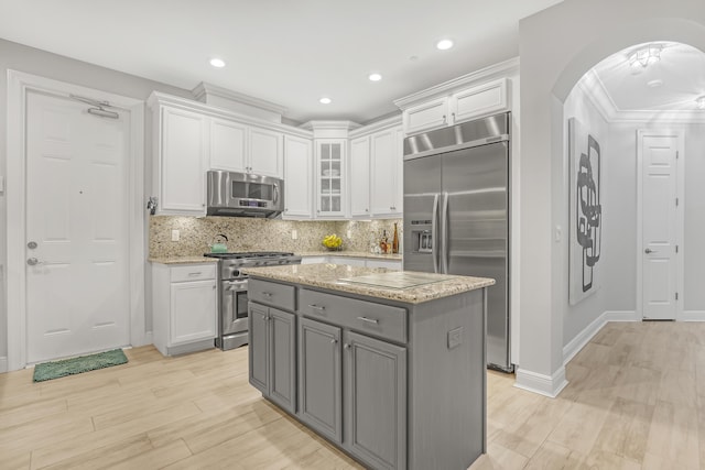 kitchen with white cabinetry, appliances with stainless steel finishes, gray cabinets, a kitchen island, and light stone countertops