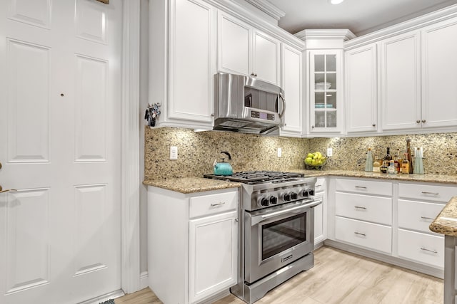 kitchen featuring tasteful backsplash, light stone counters, stainless steel appliances, light hardwood / wood-style floors, and white cabinets