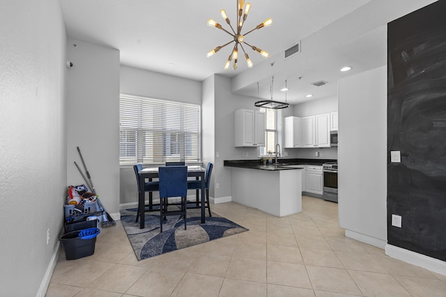 kitchen featuring white cabinetry, light tile patterned floors, decorative light fixtures, and stainless steel appliances