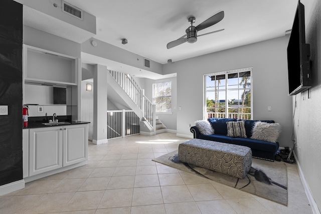 living room with sink, light tile patterned floors, built in shelves, and ceiling fan