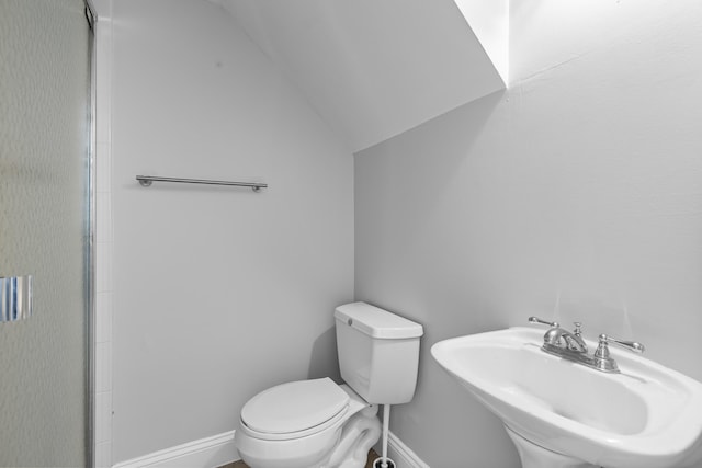 bathroom with vaulted ceiling, toilet, and sink