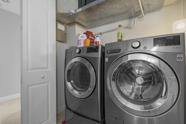 laundry area with washer and clothes dryer and light tile patterned floors