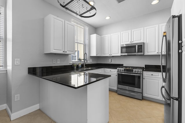 kitchen with sink, white cabinetry, light tile patterned floors, appliances with stainless steel finishes, and kitchen peninsula