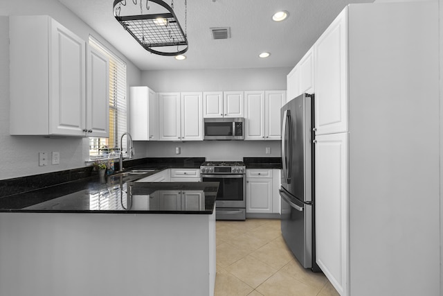 kitchen with sink, white cabinets, light tile patterned floors, kitchen peninsula, and stainless steel appliances