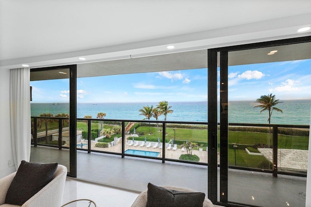 interior space with plenty of natural light, a wall of windows, a water view, and a view of the beach