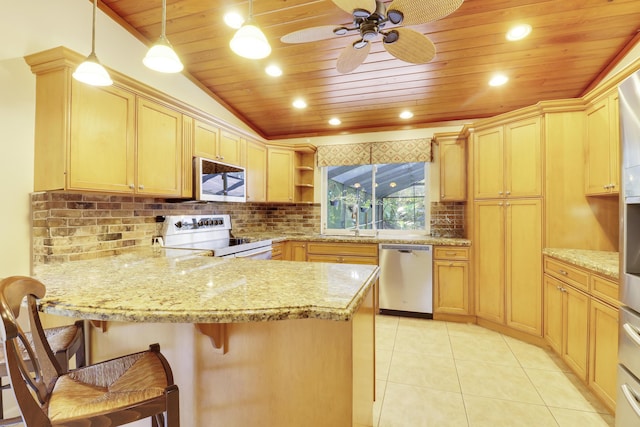 kitchen featuring pendant lighting, lofted ceiling, stainless steel appliances, light brown cabinetry, and a kitchen breakfast bar