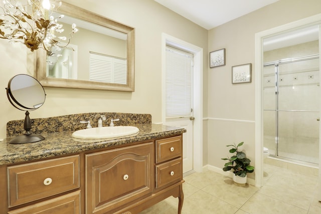 bathroom featuring toilet, vanity, tile patterned floors, and a shower with door