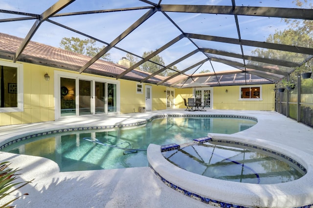 view of pool with an in ground hot tub, a patio area, and glass enclosure