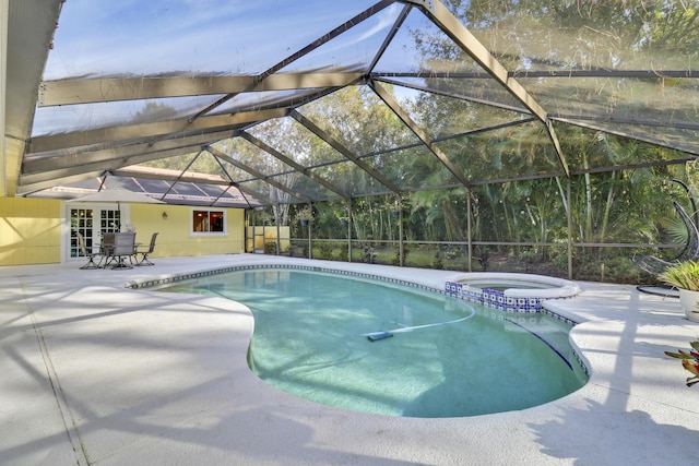 view of pool featuring glass enclosure, a patio area, and an in ground hot tub