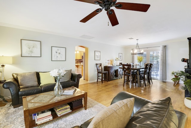 living room with ceiling fan with notable chandelier, crown molding, and light hardwood / wood-style flooring