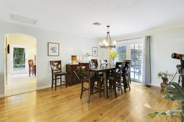 dining area featuring light wood-type flooring, an inviting chandelier, and ornamental molding