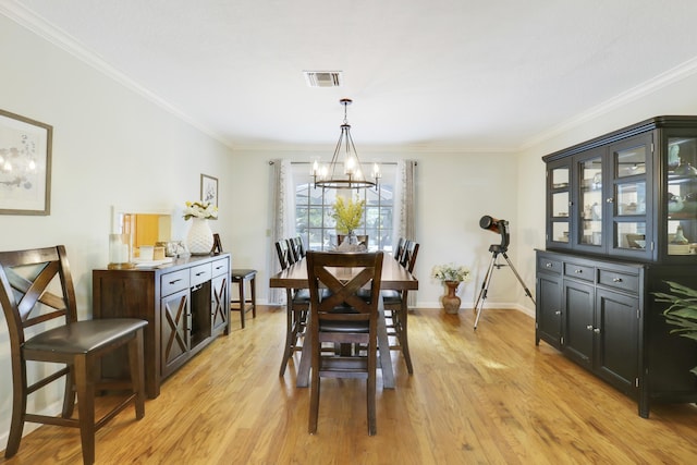 dining room with crown molding, light hardwood / wood-style flooring, and a notable chandelier