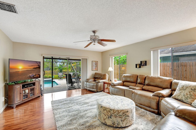 living room with plenty of natural light, a textured ceiling, and ceiling fan