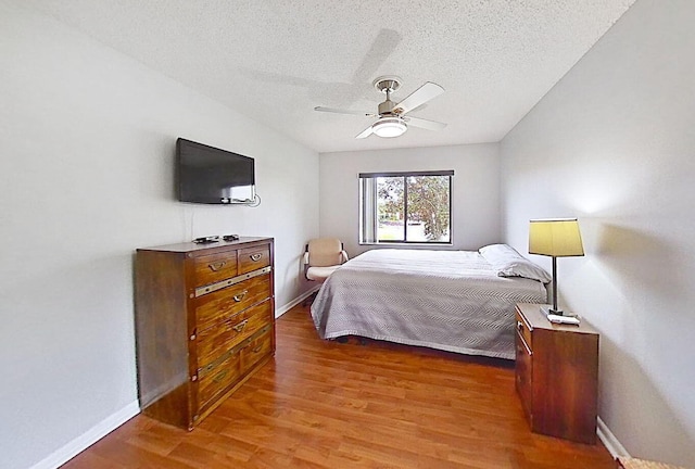 bedroom with ceiling fan, dark hardwood / wood-style floors, and a textured ceiling