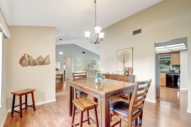 dining space with a notable chandelier, light hardwood / wood-style floors, and lofted ceiling