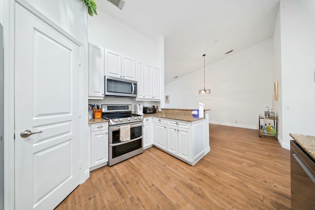 kitchen with white cabinets, decorative light fixtures, stainless steel appliances, kitchen peninsula, and vaulted ceiling