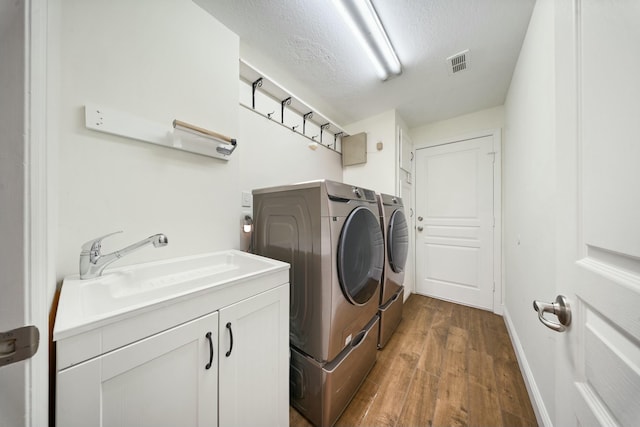 laundry area with dark hardwood / wood-style floors, sink, separate washer and dryer, a textured ceiling, and cabinets