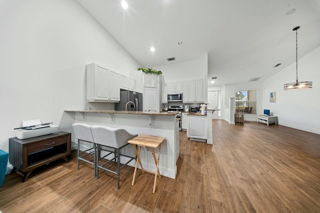 kitchen featuring light stone countertops, white cabinets, stainless steel appliances, kitchen peninsula, and light hardwood / wood-style flooring