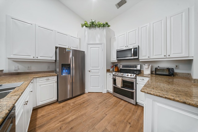 kitchen featuring lofted ceiling, sink, white cabinetry, light wood-type flooring, and stainless steel appliances