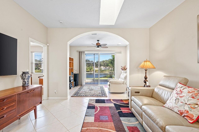 living room featuring light tile patterned floors, a textured ceiling, and ceiling fan