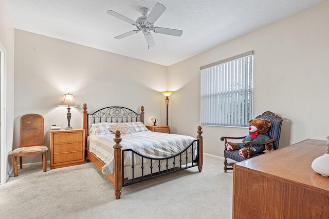 bedroom with ceiling fan, light carpet, and a textured ceiling