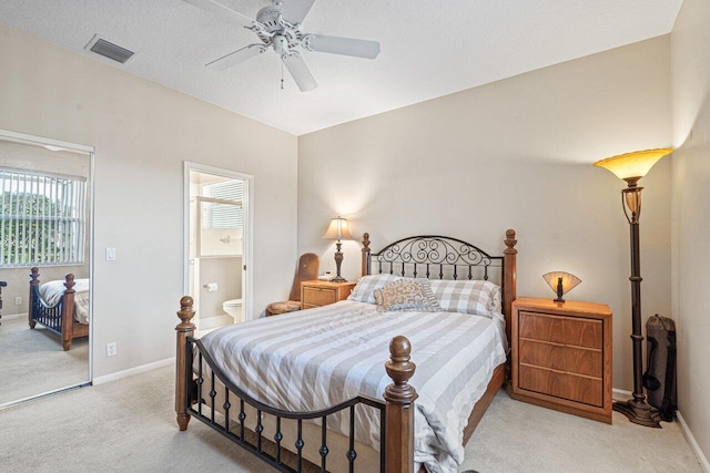 bedroom featuring ceiling fan, ensuite bath, and light carpet