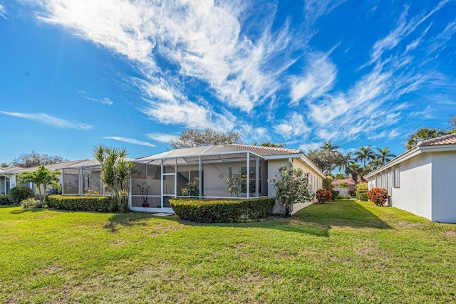 back of property with a lanai and a lawn