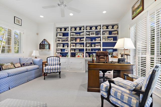 carpeted home office featuring ceiling fan, built in desk, and crown molding