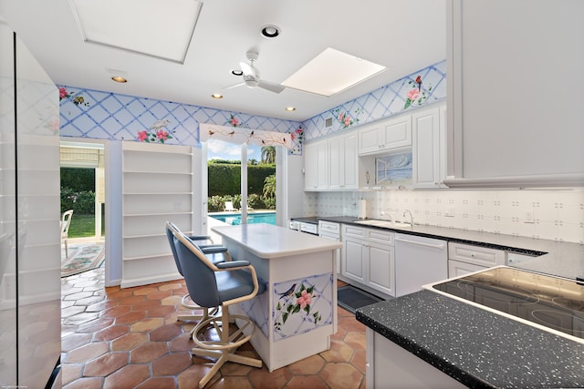 kitchen with white cabinets, dishwasher, a center island, a skylight, and a kitchen breakfast bar