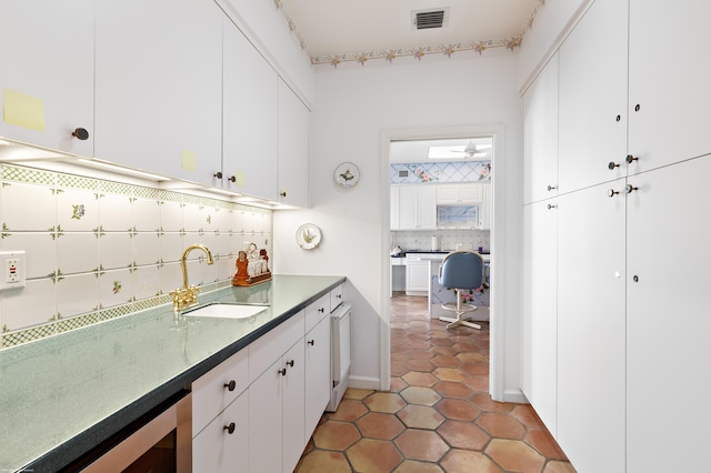 kitchen with decorative backsplash, sink, white cabinetry, and dark tile patterned flooring