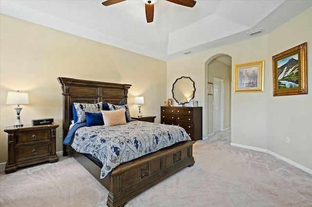 bedroom featuring light colored carpet, ceiling fan, and a tray ceiling