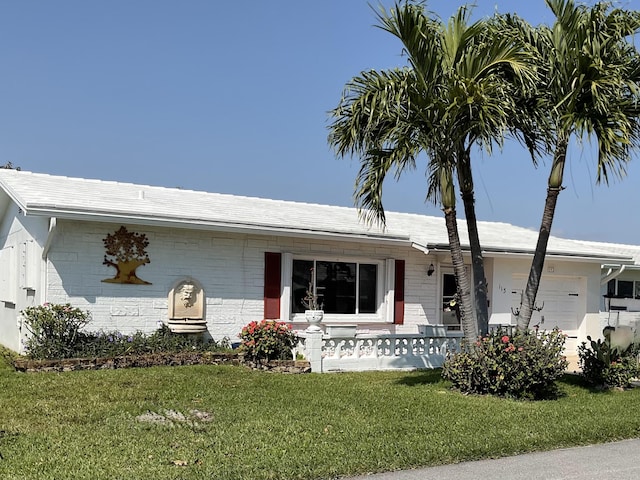 single story home featuring covered porch, brick siding, a front yard, and a garage