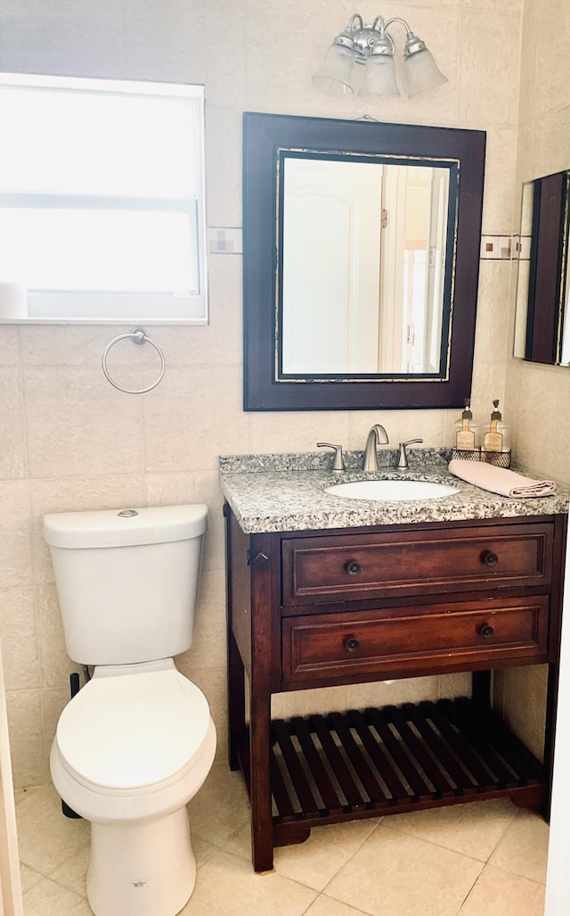 bathroom featuring toilet, tile patterned flooring, tile walls, and vanity