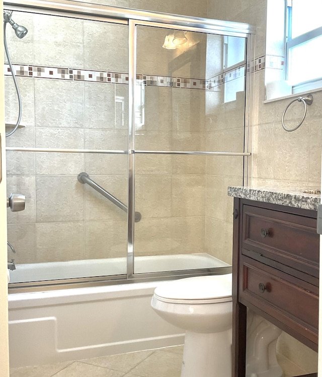 full bathroom featuring combined bath / shower with glass door, vanity, toilet, and tile patterned flooring