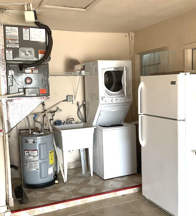 washroom featuring sink, a textured ceiling, stacked washing maching and dryer, and water heater