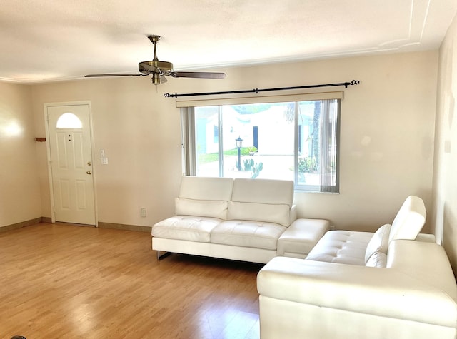 living room with light wood-style floors, a ceiling fan, and baseboards