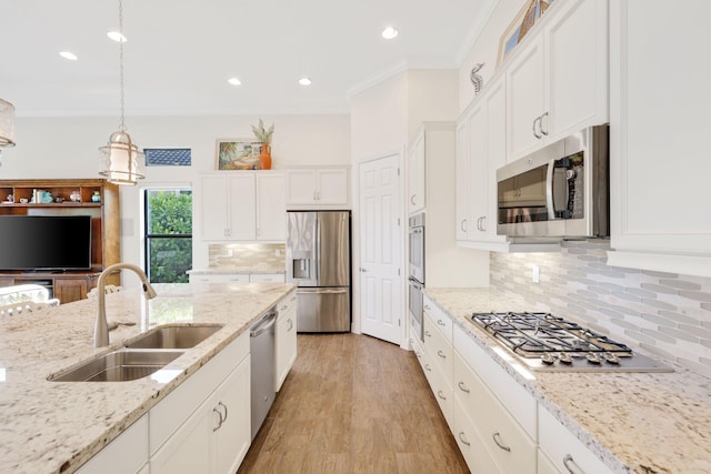 kitchen featuring white cabinetry, sink, hanging light fixtures, light stone counters, and stainless steel appliances