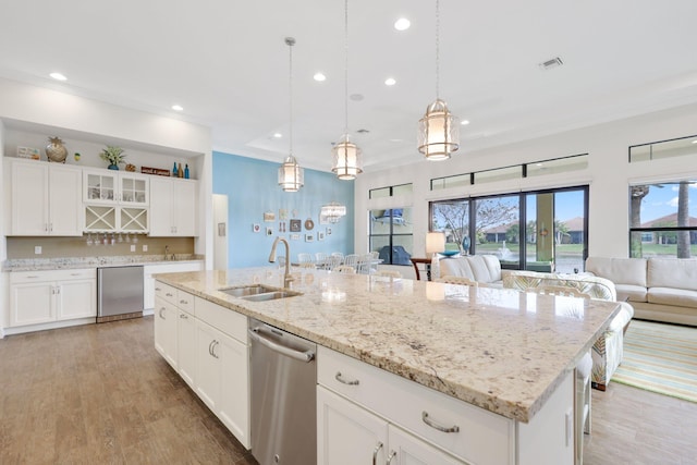 kitchen featuring white cabinetry, stainless steel dishwasher, sink, and a kitchen island with sink