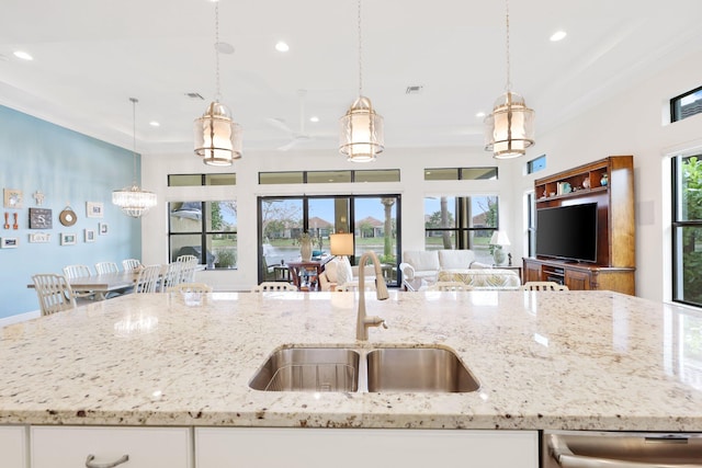 kitchen featuring pendant lighting, sink, light stone countertops, and white cabinets