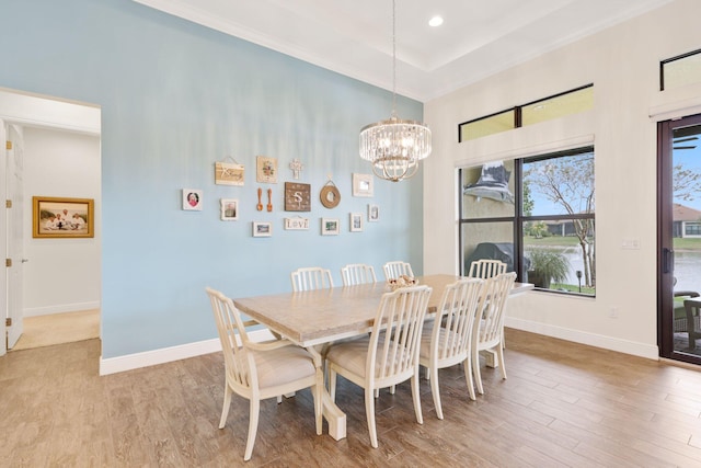 dining room with a raised ceiling, light hardwood / wood-style floors, and a notable chandelier